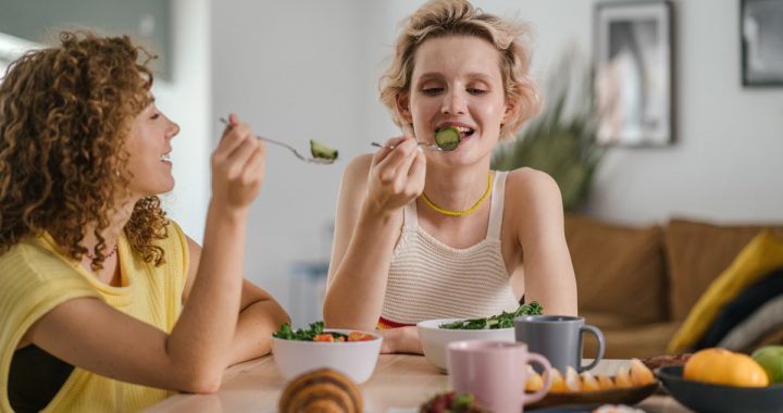 Two women enjoying a healthy meal at a cozy dining table, sharing a joyful indoor breakfast moment.
