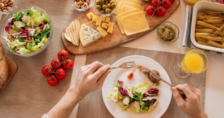 Overhead view of a cheese platter with fresh salad and juice, perfect for a gourmet lunch setting.