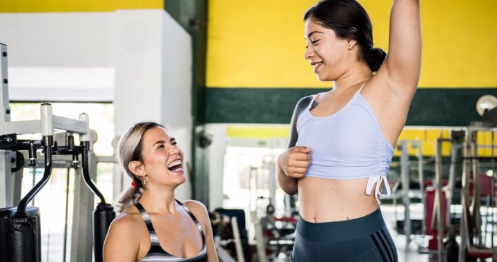 Two women in activewear sharing a joyful moment during a gym workout session.